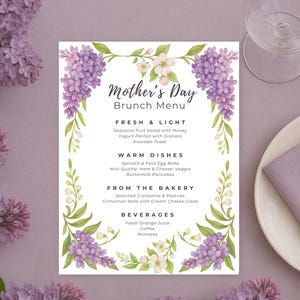 Peut inclure: Un menu de brunch pour la fête des mères imprimable avec une bordure florale. Le menu propose des options fraîches et légères, des plats chauds, des articles de la boulangerie et des boissons. La bordure florale présente des fleurs violettes et blanches.