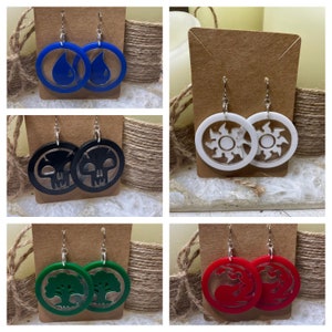May include: Four pairs of earrings featuring Magic: The Gathering symbols. The symbols are water, black, green, and red. The earrings are made of acrylic and have a silver hook.