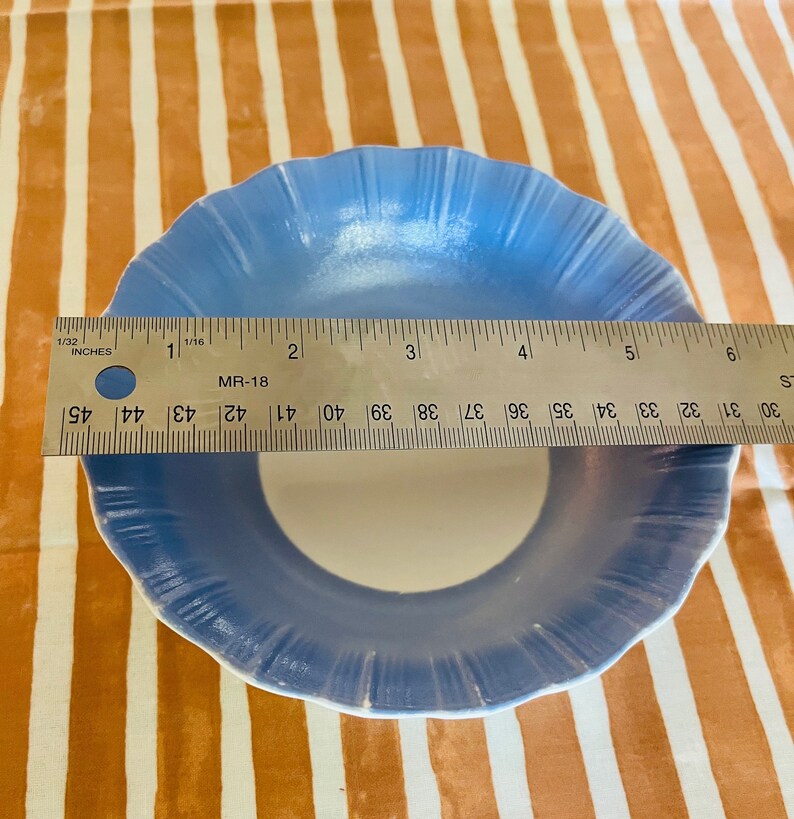 May include: A light blue ceramic bowl with a white interior and a scalloped edge. The bowl is 5 inches in diameter.