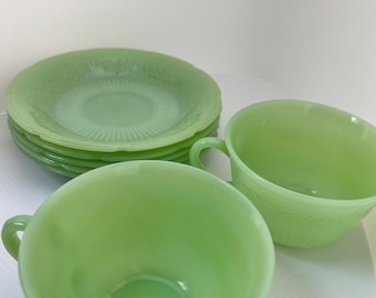 Pode incluir: Um conjunto de chávenas e pires de chá de vidro verde vintage. As chávenas e os pires têm um delicado desenho floral.