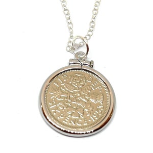 May include: A silver chain necklace with a pendant featuring a 1953 British one-penny coin. The coin is silver and has a design of a ship and the words "ONE PENNY" on it.