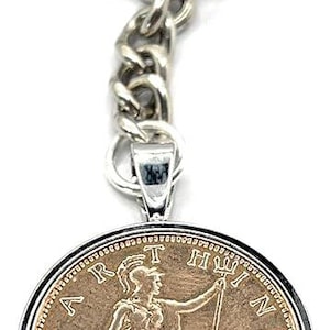 May include: Silver-toned keychain with a round pendant featuring a vintage coin. The coin has a seated figure holding a staff, with the year 1936 visible. The keychain includes a chain and a large ring.