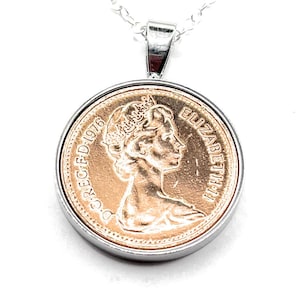 Può includere: Collana con pendente in argento con una moneta del 1976. La moneta, color rame, raffigura il profilo di una donna e l'iscrizione "ELIZABETH II D.G.REG.F.D.1976". Il pendente è appeso a una sottile catena d'argento.
