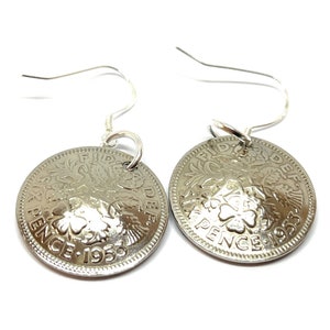 May include: Silver earrings featuring a vintage 1953 British sixpence coin with a shamrock design. The coin is attached to a silver hook earring.