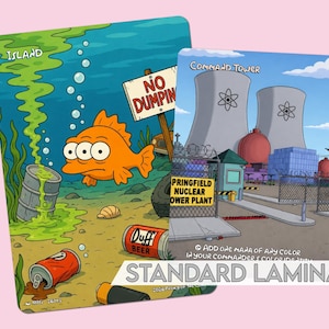 Op de afbeelding: Twee ge&iuml;llustreerde kaarten met cartoonsc&egrave;nes. E&eacute;n toont een oranje vis in vervuild water met een bordje "No Dumping". De andere toont een kerncentrale. De tekst "Springfield Nuclear Power Plant" is zichtbaar.