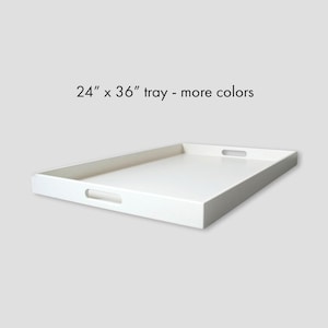 May include: A rectangular white tray with integrated cutout handles on the shorter sides. The tray features a smooth, solid surface and clean edges. Text printed above the tray reads 24" x 36" tray - more colors, indicating the dimensions.