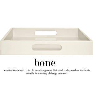 May include: A rectangular off-white tray with a smooth finish and two integrated oval handles on the sides. The text "bone" is printed below the tray, followed by the description: "A soft off-white with a hint of cream brings a sophisticated, understated neutral that is suitable for a variety of design aesthetics."