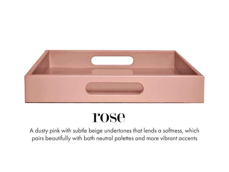 May include: A rectangular dusty pink tray with a smooth finish and two integrated oval handles on the sides. The text below the tray reads: rose. A dusty pink with subtle beige undertones that lends a softness, which pairs beautifully with both neutral palettes and more vibrant accents.