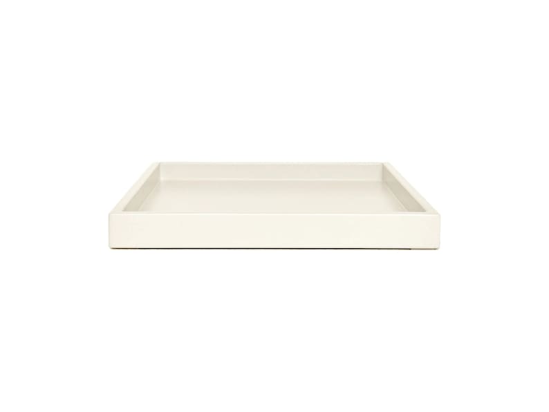 May include: A rectangular tray with a smooth, solid off-white finish. The tray features a flat base and raised, straight edges that form a clean, simple border around the perimeter, creating a shallow, open container for holding various small items.