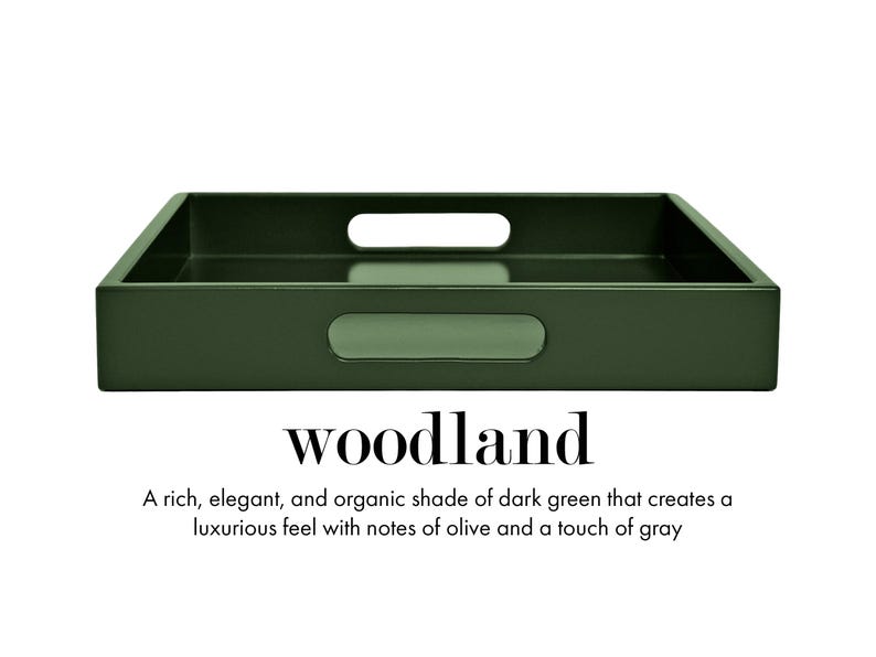 May include: A rectangular dark green serving tray with integrated handles on the sides. The text "woodland" is printed below the tray, followed by the description: "A rich, elegant, and organic shade of dark green that creates a luxurious feel with notes of olive and a touch of gray."