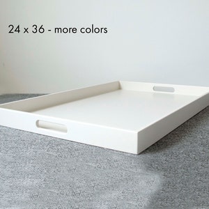 May include: A rectangular white serving tray with cut-out handles. The tray measures 24 inches by 36 inches. The text "24 x 36 - more colors" is visible in the image. The tray is placed on a gray surface.
