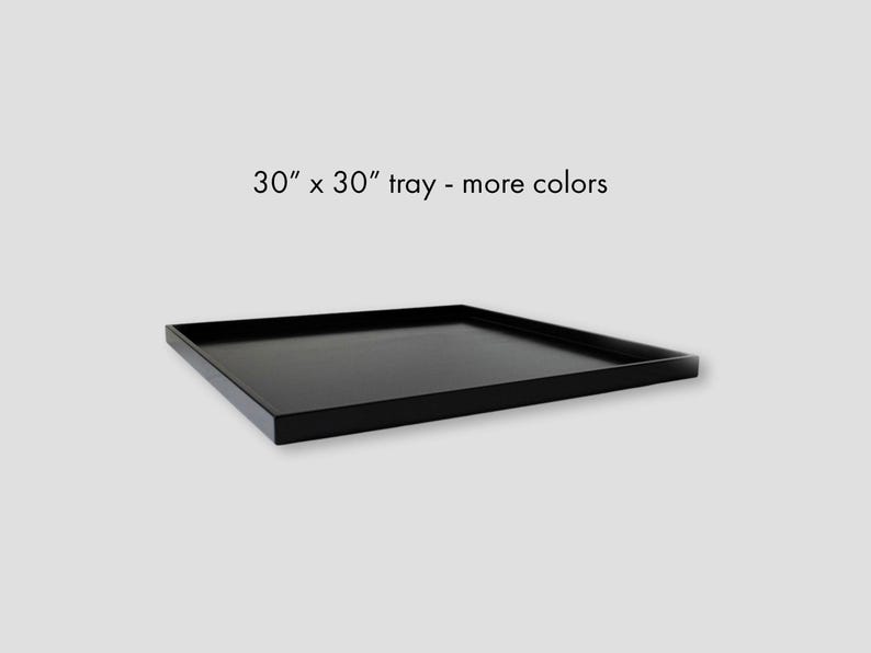 Może przedstawiać: Czarna, kwadratowa taca o wymiarach 76 cm na 76 cm. Taca ma prosty, nowoczesny design z podniesioną krawędzią. Tekst na zdjęciu brzmi: "30" x 30" tray - more colors."