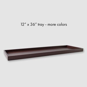 May include: A rectangular, dark brown tray, measuring 12 inches by 36 inches. The tray has a low, raised edge and a simple, modern design. Text on the image reads "12" x 36" tray - more colors."