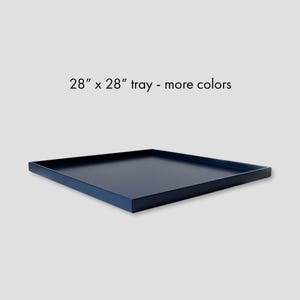 May include: A square navy blue tray with a flat base and raised edges. The text above the tray reads 28" x 28" tray - more colors. The tray has a smooth, matte finish and is positioned at an angle to show its depth and square shape.