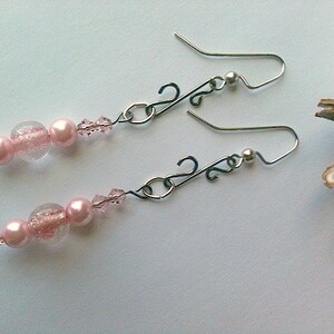 May include: A pair of dangle earrings with pink and clear glass beads and silver-toned metal hooks.