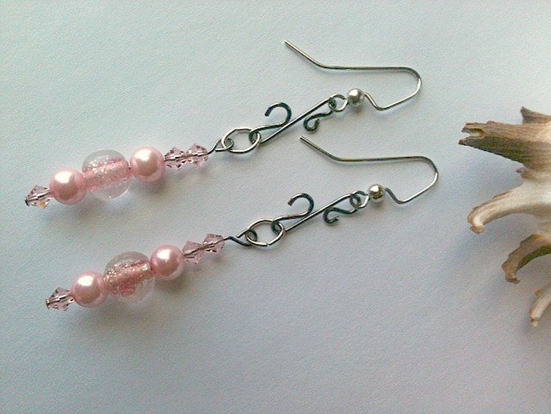 May include: A pair of dangle earrings with pink and clear glass beads and silver-toned metal hooks.