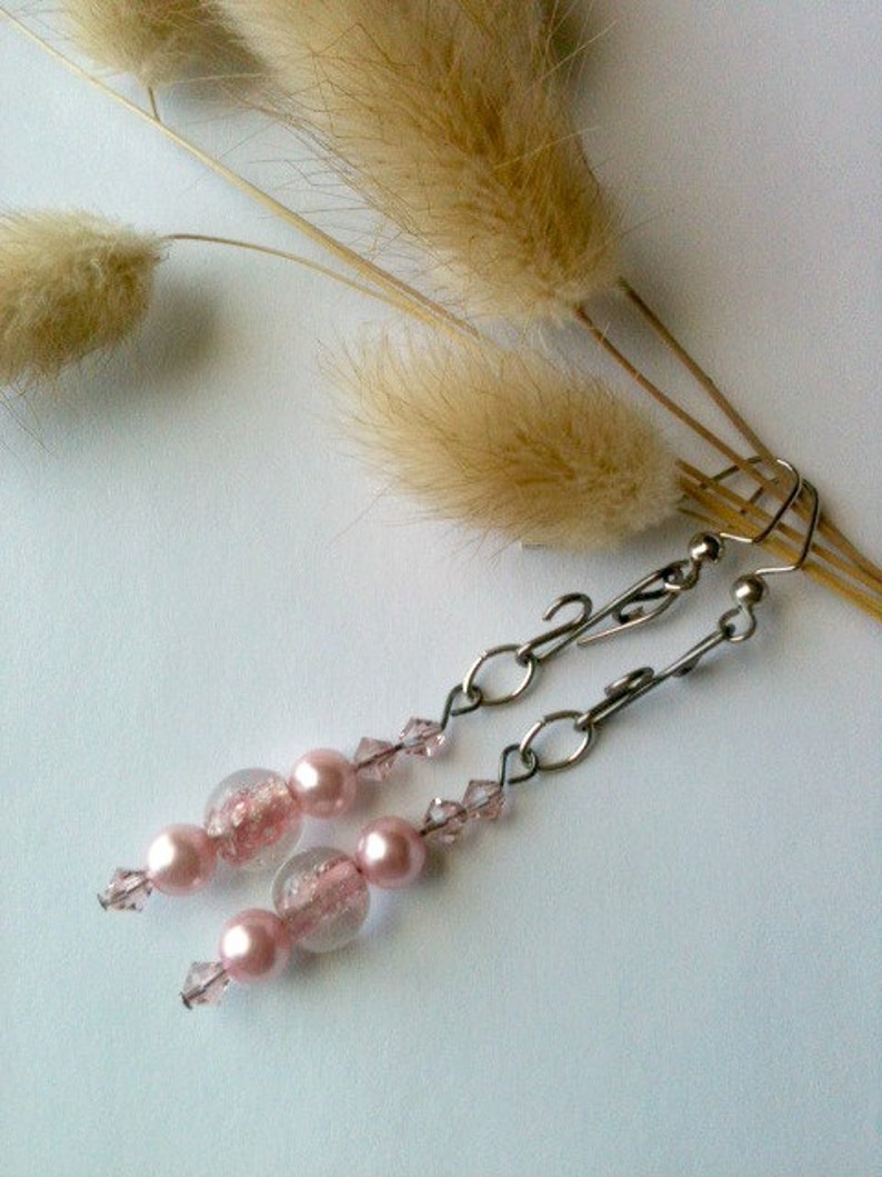 May include: Pink and clear glass bead earrings with silver chain and crystal accents.
