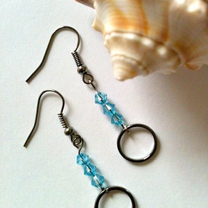 May include: A pair of silver earrings with a small circle charm and blue crystal beads.
