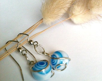 May include: A pair of silver earrings with blue and white swirl glass beads wrapped in silver wire.