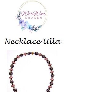 May include: A necklace with a cross pendant made of purple and pink beads. The necklace is made of small beads and has a delicate look.