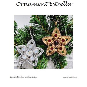 May include: Two beaded star ornaments, one silver and one gold, hang against a backdrop of evergreen branches. The silver star features clear and iridescent beads, while the gold star has red and brown accents. The text "Ornament Estrella" is above the ornaments.
