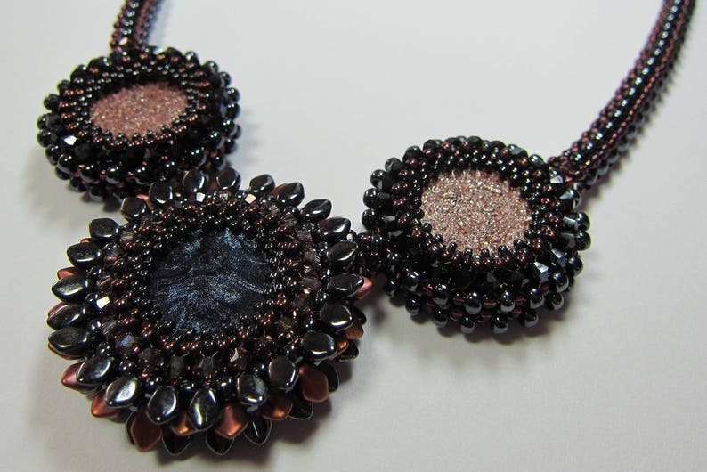May include: A beaded necklace with three large, round pendants. The pendants are made of dark brown and black beads and have a metallic sheen. The center pendant is larger than the other two and has a dark blue center.