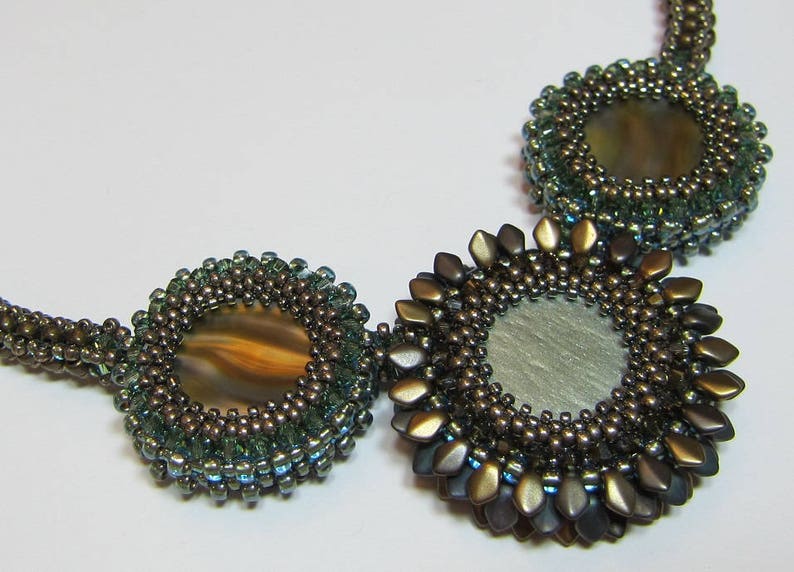 May include: A beaded necklace with three circular pendants. The pendants are made of brown and green beads and feature a round, iridescent stone in the center.