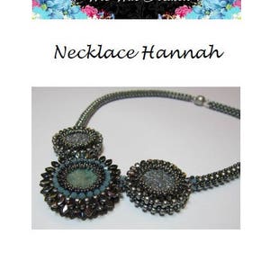 May include: A silver necklace with three round, beaded pendants. The pendants are in shades of gray and blue. The necklace is called "Necklace Hannah" and is from the website "Wir War Kralen".
