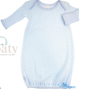 May include: A light blue baby gown with long sleeves and a woven pattern. The gown features a light blue trim around the neckline and cuffs, and a small bow at the bottom. The gown is made of a soft, knitted material.