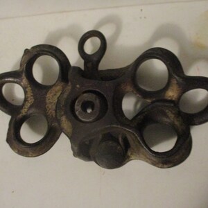 May include: A vintage cast iron pulley with six holes, featuring a worn, dark brown finish.