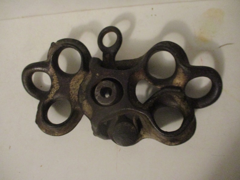 May include: A vintage cast iron pulley with six holes, featuring a worn, dark brown finish.