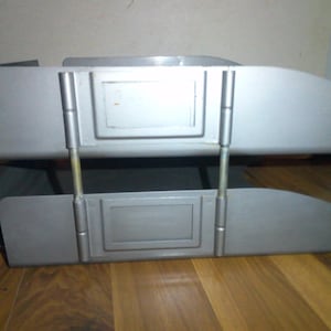 May include: A silver metal two-tiered file organizer with a rectangular opening on each tier.