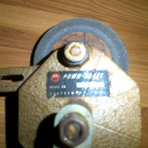 May include: A close-up of a gold-colored Power-Craft grinding wheel with a black label that reads "Power-Craft" and "Model No. 100000".