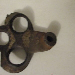 May include: A vintage, rusty, metal key with three holes and a round end. The key is brown and has a worn, aged appearance.