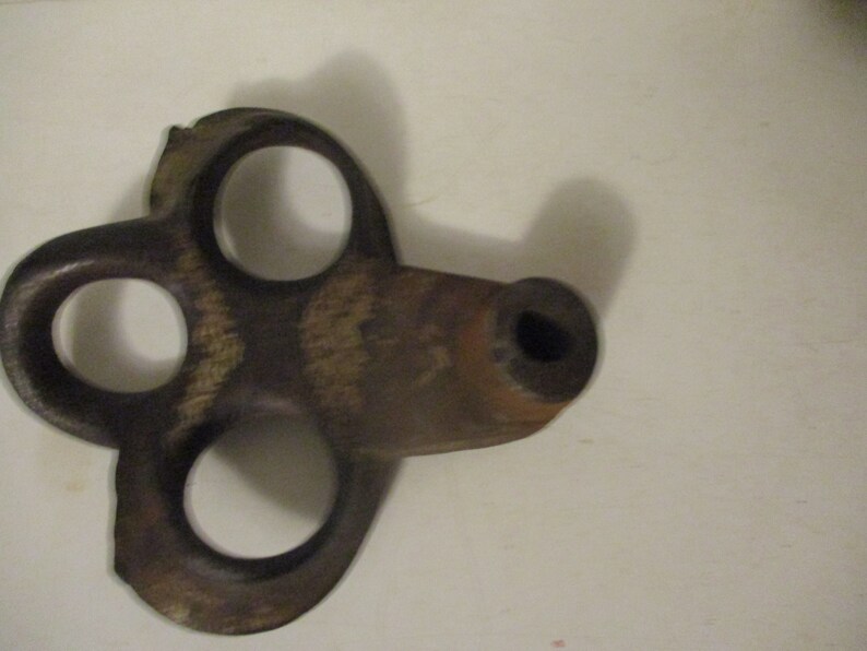 May include: A vintage, rusty, metal key with three holes and a round end. The key is brown and has a worn, aged appearance.