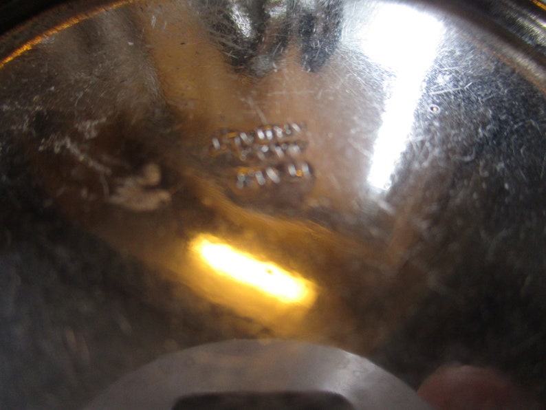 Op de afbeelding: Close-up van de bodem van een zilveren metalen kom met de tekst "Stainless Steel Made in USA" gestempeld op de bodem.