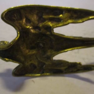 K&ouml;nnte beinhalten: Vintage Vogel-Figur aus Messing, vermutlich ein K&uuml;hlerfigur. Der Vogel wird im Flug mit ausgebreiteten Fl&uuml;geln dargestellt. Das Messing hat eine warme, gealterte Patina, die auf sein Alter hindeutet. Die Skulptur ist detailliert und zeigt die Federn und Form des Vogels.