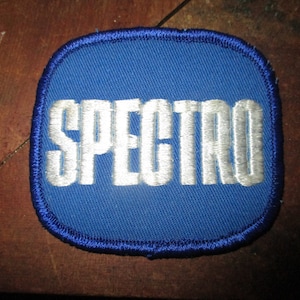 May include: A blue embroidered patch with the word "SPECTRO" in white lettering.