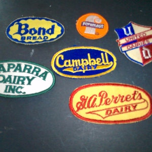 May include: A collection of vintage embroidered patches featuring various brands, including Bond Bread, Faremost, United Dairies, Caparra Dairy Inc., Campbell Dairy, and St. Perrets Dairy.