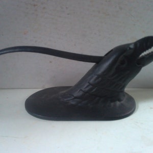 May include: Black cast iron nutcracker shaped like a bird's head with an open beak. The nutcracker has a long, curved handle.