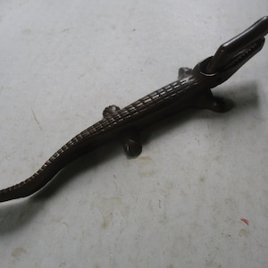 May include: A cast iron alligator nutcracker with a textured, alligator-skin design. The nutcracker is open, ready to crack nuts.