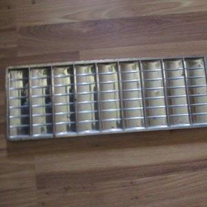 May include: A silver metal baking pan with a grid pattern. The pan is designed for making multiple small treats, such as cookies or candies.