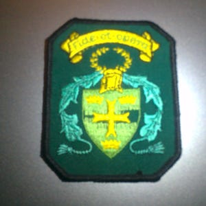 May include: Green embroidered patch with a yellow crest and the text "Fide et Forti" in a yellow banner.