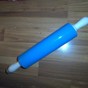 May include: A blue rolling pin with white handles. The rolling pin is made of a smooth, hard material and is perfect for rolling out dough.