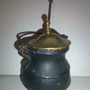 May include: A small black cast iron pot with a brass lid and a brass handle. The pot has three legs and is about 6 inches tall.