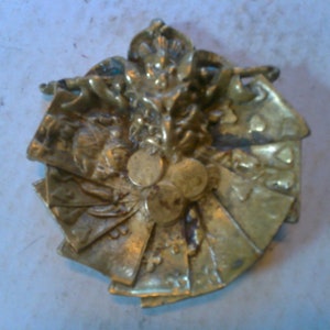 May include: A gold-toned metal ornament shaped like a jester's hat with playing cards around it.