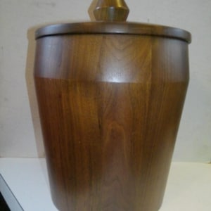 May include: A wooden ice bucket with a lid. The bucket is brown and has a smooth finish. The lid has a knob on top.