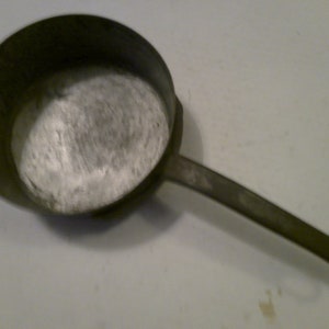 May include: A vintage aluminum saucepan with a long handle. The saucepan is empty and has a silver finish.
