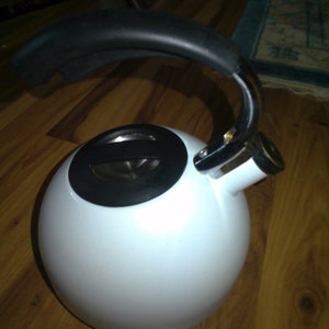 May include: White kettle with a black lid and a black handle. The kettle has a chrome spout and a chrome base.