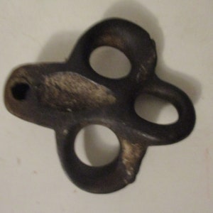 May include: A dark gray metal hook with three holes. The hook is shaped like a clover leaf.